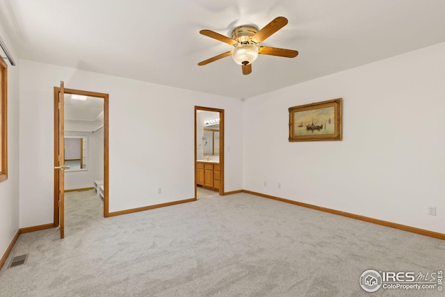 interior space with ceiling fan, light colored carpet, and ensuite bath