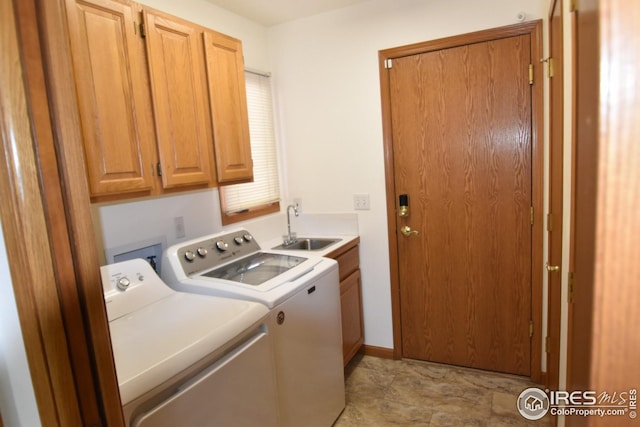 clothes washing area with washer and dryer, cabinets, and sink