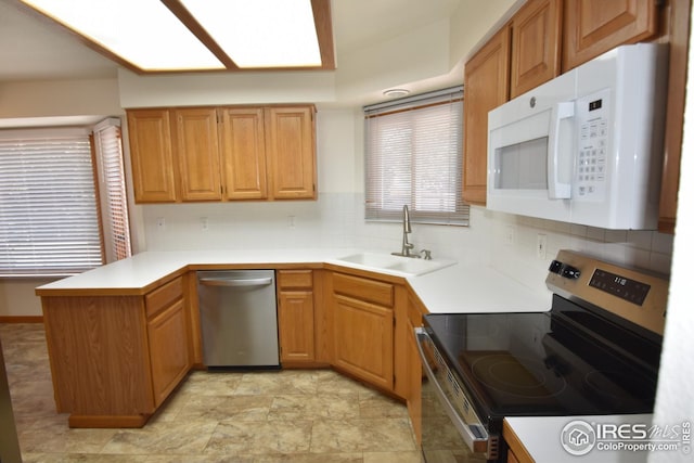 kitchen with decorative backsplash, sink, kitchen peninsula, and stainless steel appliances