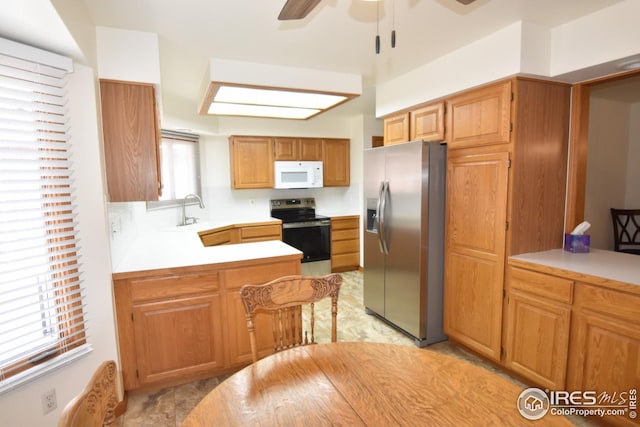 kitchen with kitchen peninsula, stainless steel appliances, ceiling fan, and sink