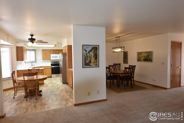 kitchen featuring ceiling fan, sink, decorative light fixtures, light carpet, and stainless steel stove