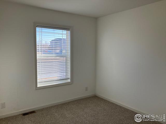 empty room with baseboards, visible vents, and carpet flooring