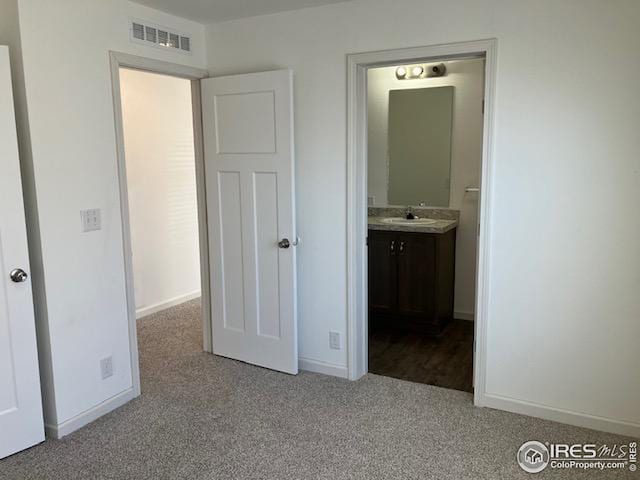 unfurnished bedroom with connected bathroom, carpet flooring, visible vents, and baseboards