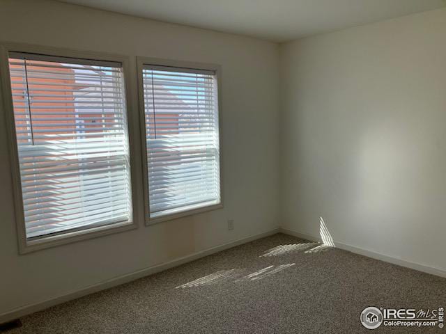 unfurnished room with carpet flooring and baseboards