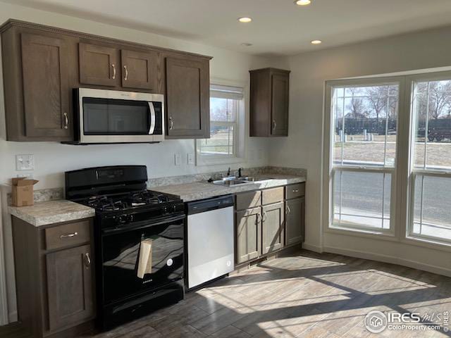 kitchen featuring dark brown cabinets, appliances with stainless steel finishes, a sink, and light countertops