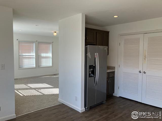 kitchen with dark brown cabinets, baseboards, stainless steel refrigerator with ice dispenser, and dark wood finished floors