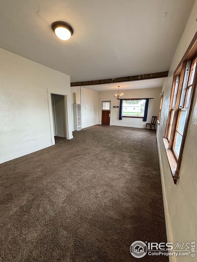 unfurnished living room with dark colored carpet and a notable chandelier