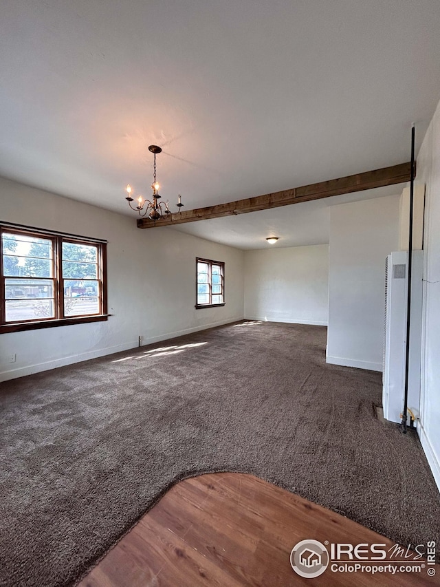 carpeted spare room featuring a chandelier and a wealth of natural light