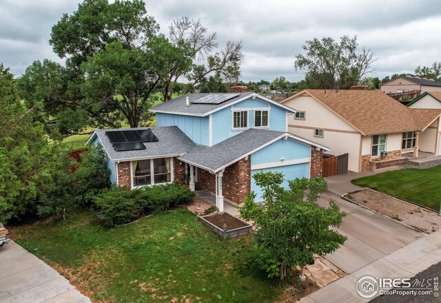 view of front of home featuring a garage, solar panels, and a front yard