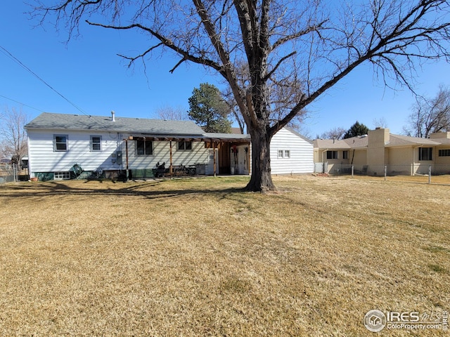 rear view of property featuring a lawn and fence