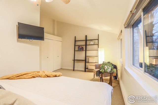 bedroom with lofted ceiling, a closet, light carpet, and baseboards