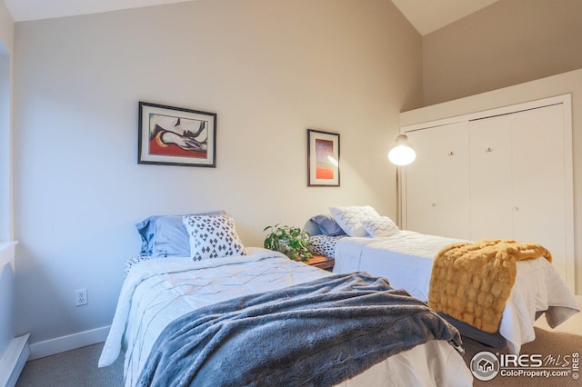 carpeted bedroom with a closet, vaulted ceiling, and baseboards