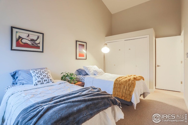 bedroom featuring vaulted ceiling, a closet, and light colored carpet