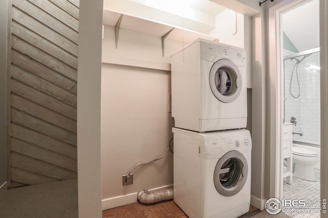 washroom with laundry area, stacked washing maching and dryer, tile patterned flooring, and baseboards