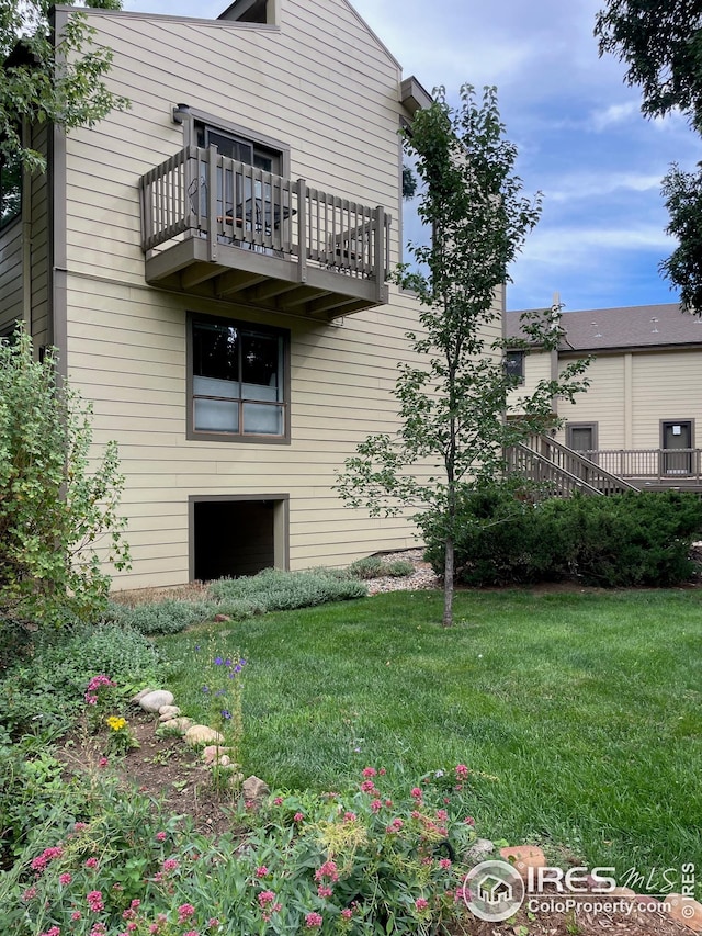 rear view of house featuring a lawn and a balcony