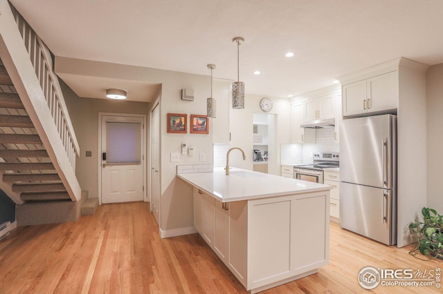 kitchen with a peninsula, stainless steel appliances, a sink, white cabinetry, and pendant lighting