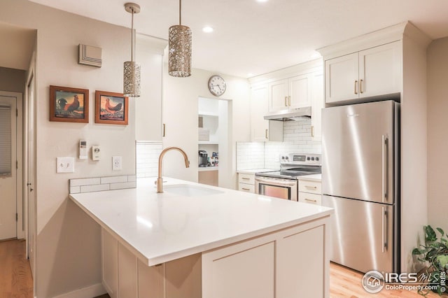 kitchen featuring a peninsula, appliances with stainless steel finishes, light countertops, and under cabinet range hood