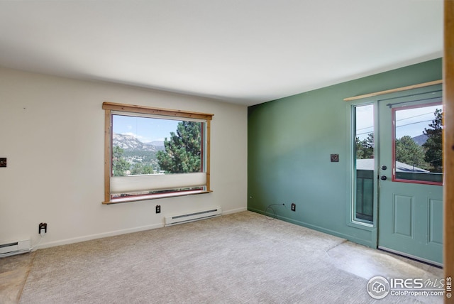 carpeted spare room featuring baseboard heating and plenty of natural light