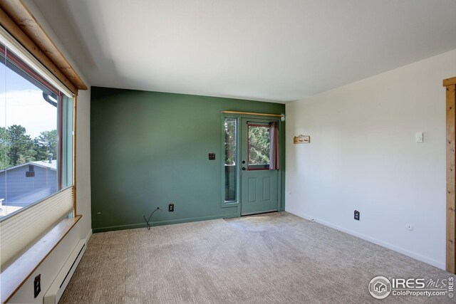 carpeted spare room with a baseboard radiator and a wealth of natural light