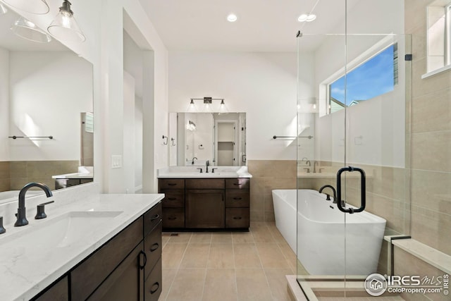 bathroom featuring tile patterned floors, vanity, tile walls, and independent shower and bath