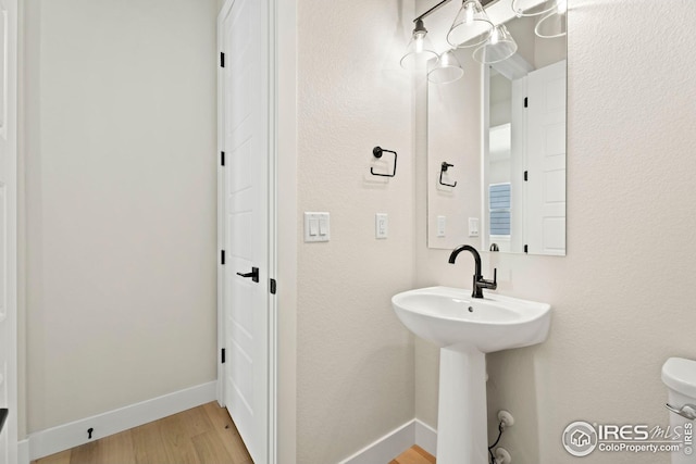 bathroom featuring wood-type flooring, toilet, and sink