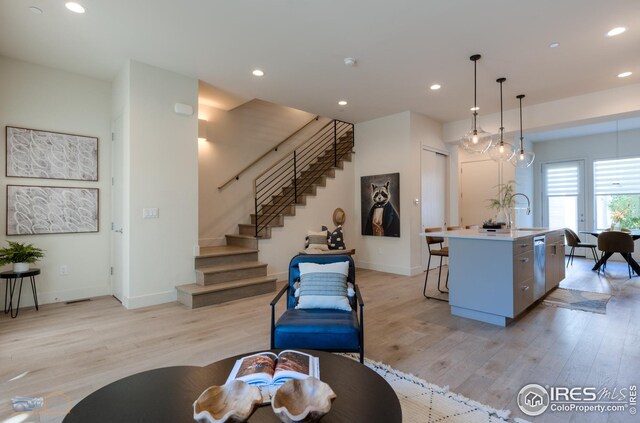 living area featuring recessed lighting, light wood-style floors, and stairs