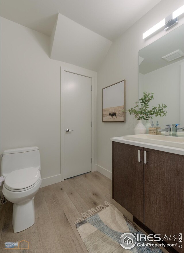 bathroom featuring visible vents, toilet, wood finished floors, baseboards, and vanity