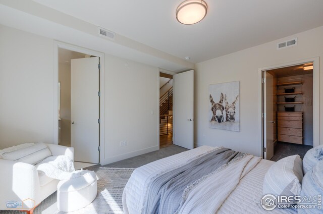 bedroom featuring a walk in closet, a closet, visible vents, and carpet floors