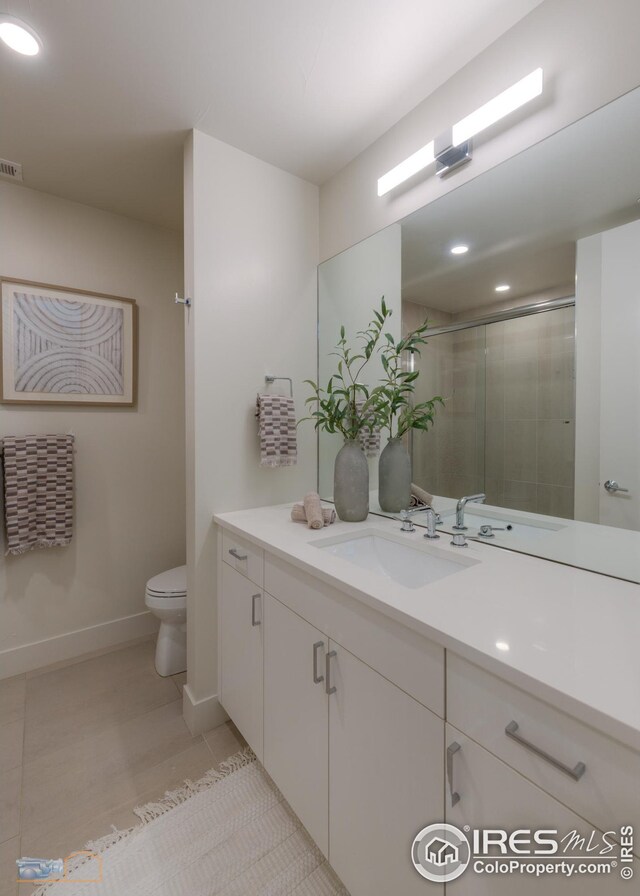 bathroom with vanity, a shower with shower door, baseboards, tile patterned flooring, and toilet