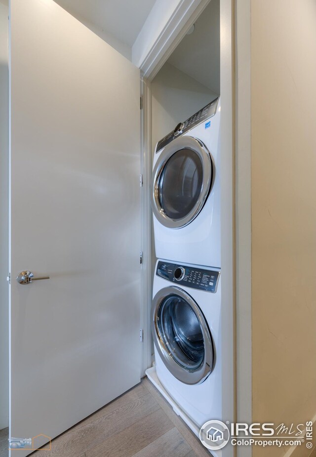 laundry room with stacked washer and dryer, laundry area, and light wood finished floors
