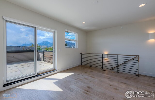 empty room featuring recessed lighting, a mountain view, baseboards, and wood finished floors