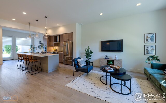 living room featuring recessed lighting, baseboards, and light wood-style floors
