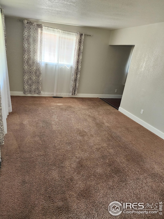 unfurnished room featuring a textured ceiling and carpet flooring