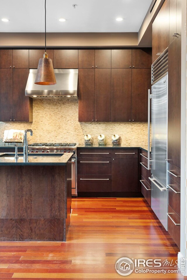 1155 Canyon Blvd Unit 205, Boulder, CO 80302 - kitchen with wall chimney exhaust hood, built in fridge, light wood finished floors, and dark brown cabinets