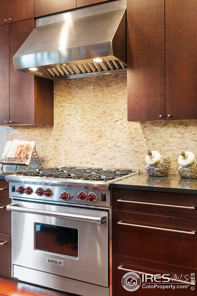 1155 Canyon Blvd Unit 205, Boulder, CO 80302 - kitchen with premium stove, wall chimney exhaust hood, tasteful backsplash, and dark brown cabinets