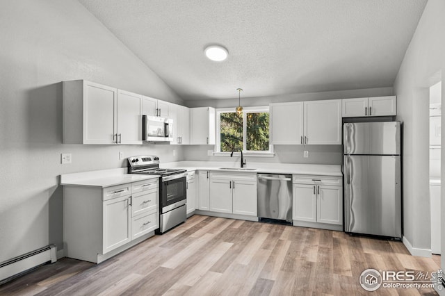 kitchen with lofted ceiling, sink, white cabinetry, stainless steel appliances, and a baseboard radiator