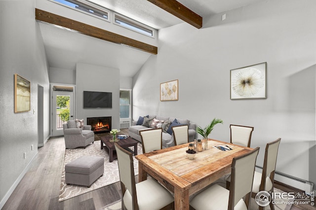 dining area featuring lofted ceiling with beams, baseboard heating, and light hardwood / wood-style flooring