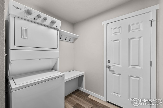 laundry room featuring stacked washer / dryer and dark hardwood / wood-style floors