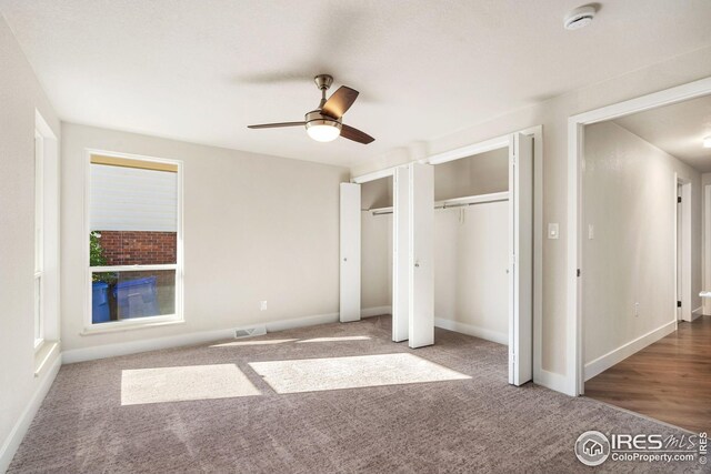 unfurnished bedroom featuring carpet flooring, two closets, and ceiling fan