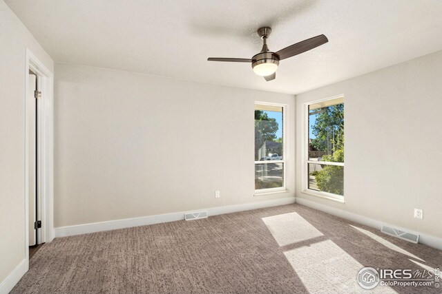 carpeted spare room featuring ceiling fan