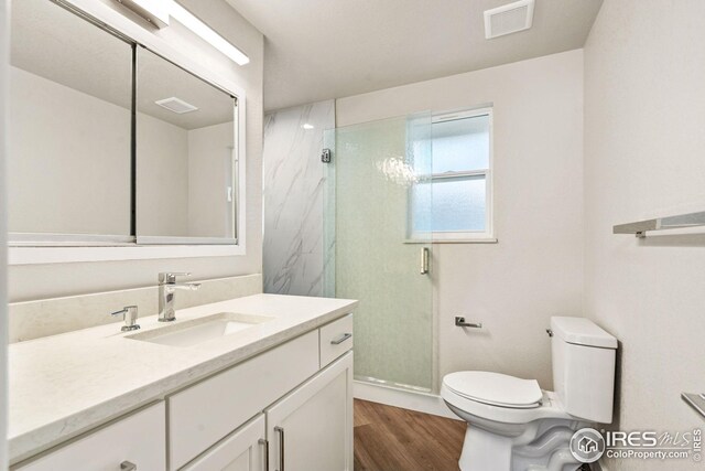 bathroom featuring vanity, hardwood / wood-style floors, toilet, and an enclosed shower