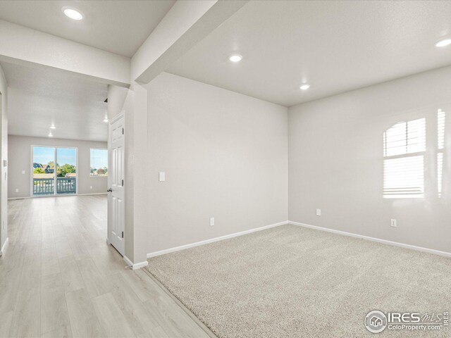 unfurnished room with beamed ceiling and light hardwood / wood-style floors