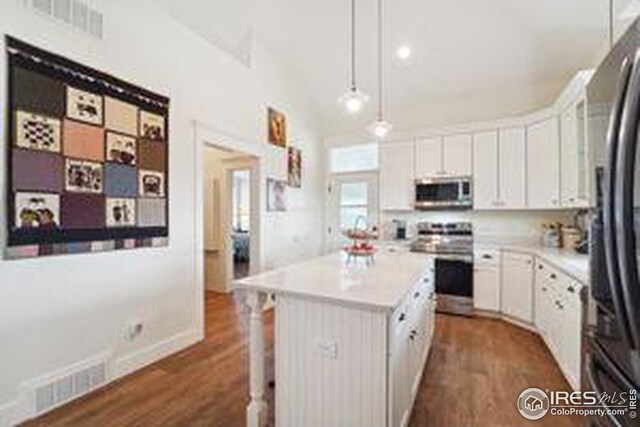 kitchen with white cabinets, appliances with stainless steel finishes, pendant lighting, and a center island