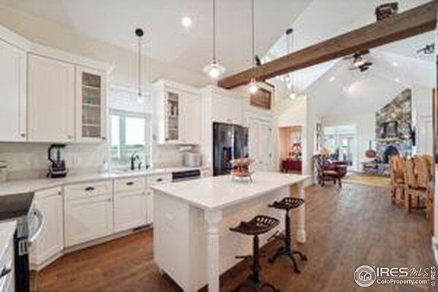 kitchen featuring lofted ceiling with beams, white cabinets, and a center island