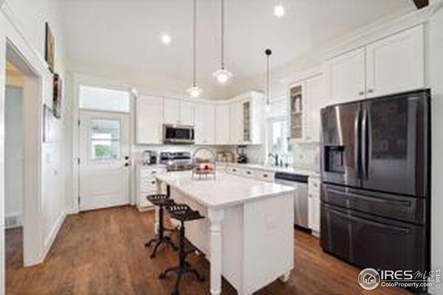 kitchen with white cabinets, pendant lighting, a kitchen island, stainless steel appliances, and a breakfast bar