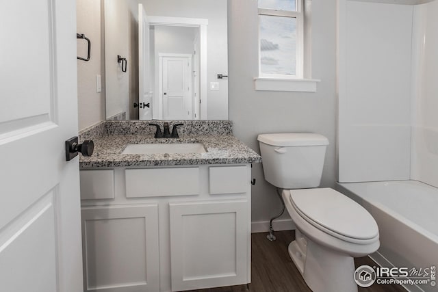 1215 105th Avenue Ct, Greeley, CO 80634 - full bath with baseboards, toilet, vanity, and wood finished floors