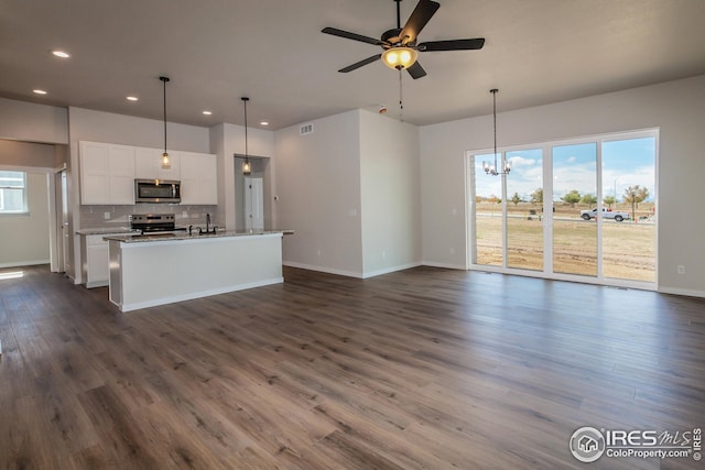 1215 105th Avenue Ct, Greeley, CO 80634 - kitchen featuring tasteful backsplash, dark wood finished floors, stainless steel appliances, ceiling fan with notable chandelier, and white cabinets