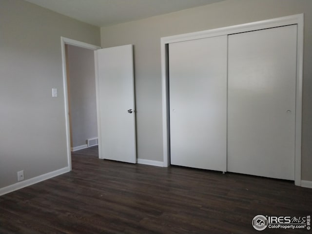 unfurnished bedroom featuring a closet and dark wood-type flooring