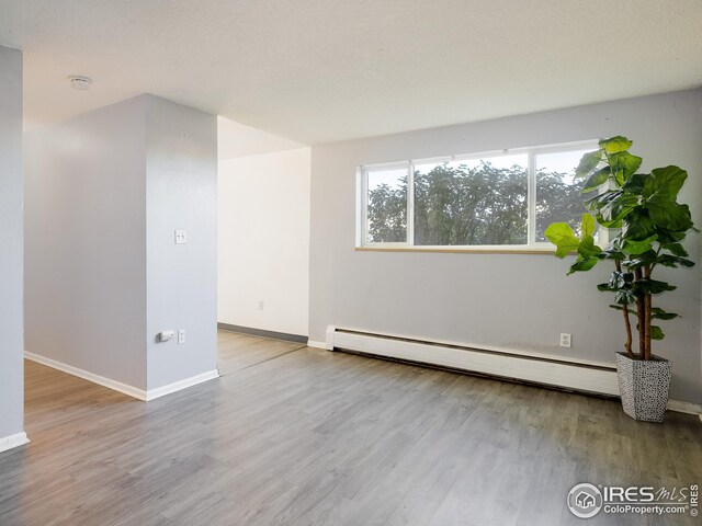 1391 Lima St, Aurora, CO 80010 - spare room featuring a baseboard heating unit, wood finished floors, baseboards, and a smoke detector