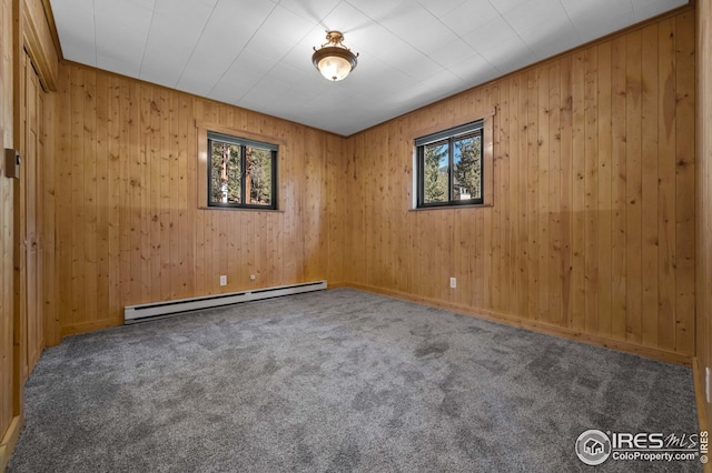 spare room featuring carpet floors, wooden walls, baseboards, and baseboard heating
